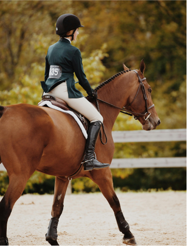 Girl in green blazer riding a horse
