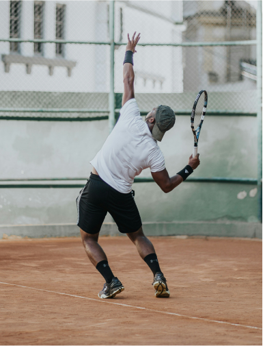 Tennis player serving a tennis ball mid air
